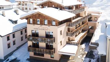Ein mehrstöckiges Hotel mit Balkonen und einer Skipiste im Hintergrund.
