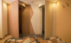 A bathroom with a unique tiled wall design, a curved shower area, and a mosaic floor pattern. - Hotel Abendrot by Alpeffect Hotels (Ischgl)