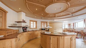 A spacious kitchen with wooden cabinets, a central island, and a dining area with tables and chairs. - Hotel Abendrot by Alpeffect Hotels (Ischgl)