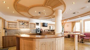 A wooden interior with a central bar area, kitchen, and seating area. - Hotel Abendrot by Alpeffect Hotels (Ischgl)