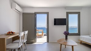 A modern hotel room with a balcony, a dining area, and a TV. - Kymo Luxury Suites Paros (Paros)