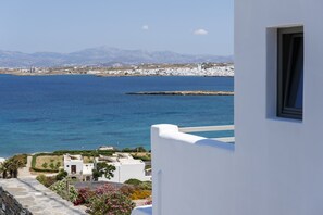 A coastal view with a white building, a clear blue sea, and distant mountains. - Kymo Luxury Suites Paros (Paros)