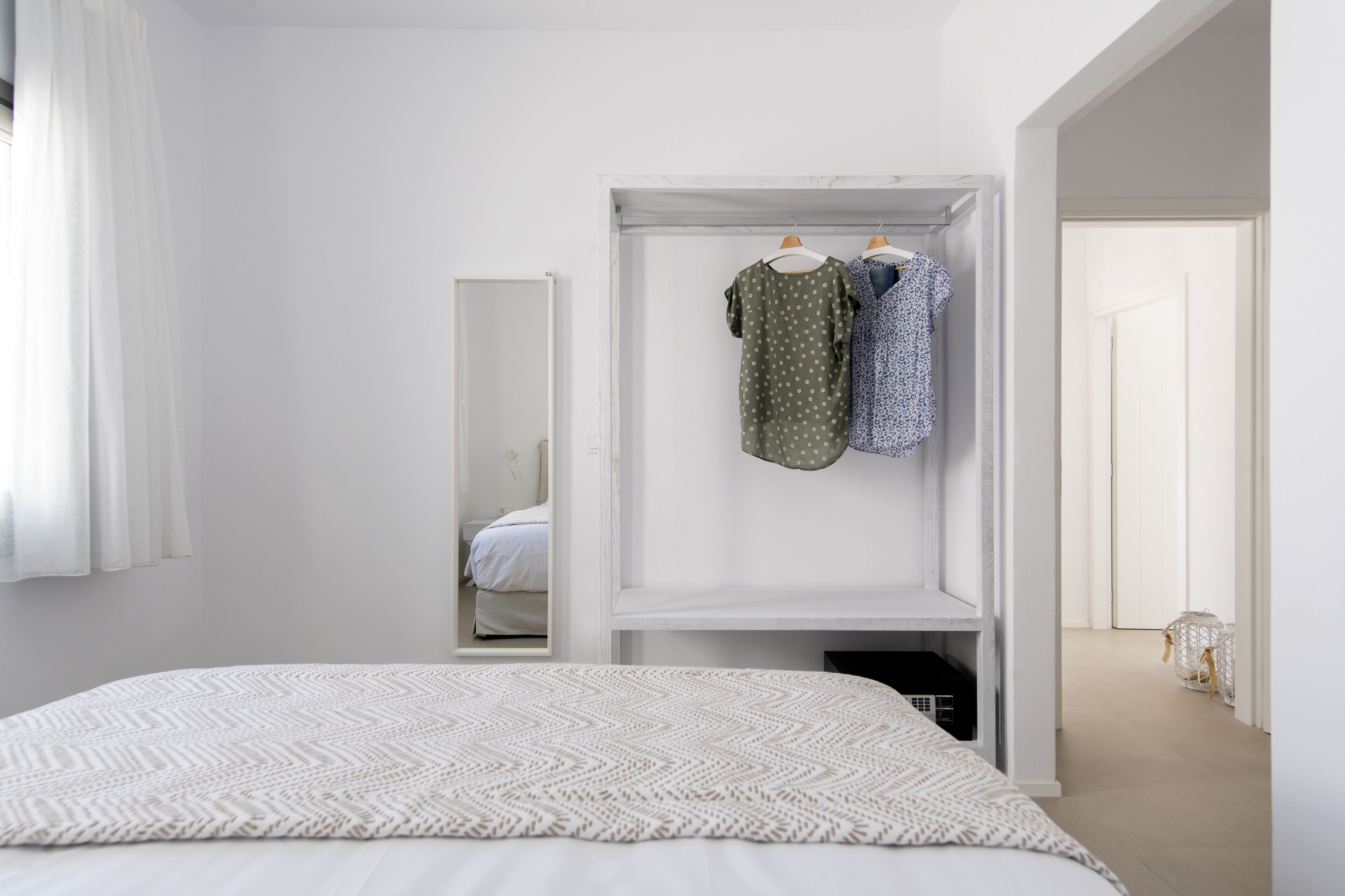 A minimalist bedroom with a bed, a wardrobe, and a mirror.