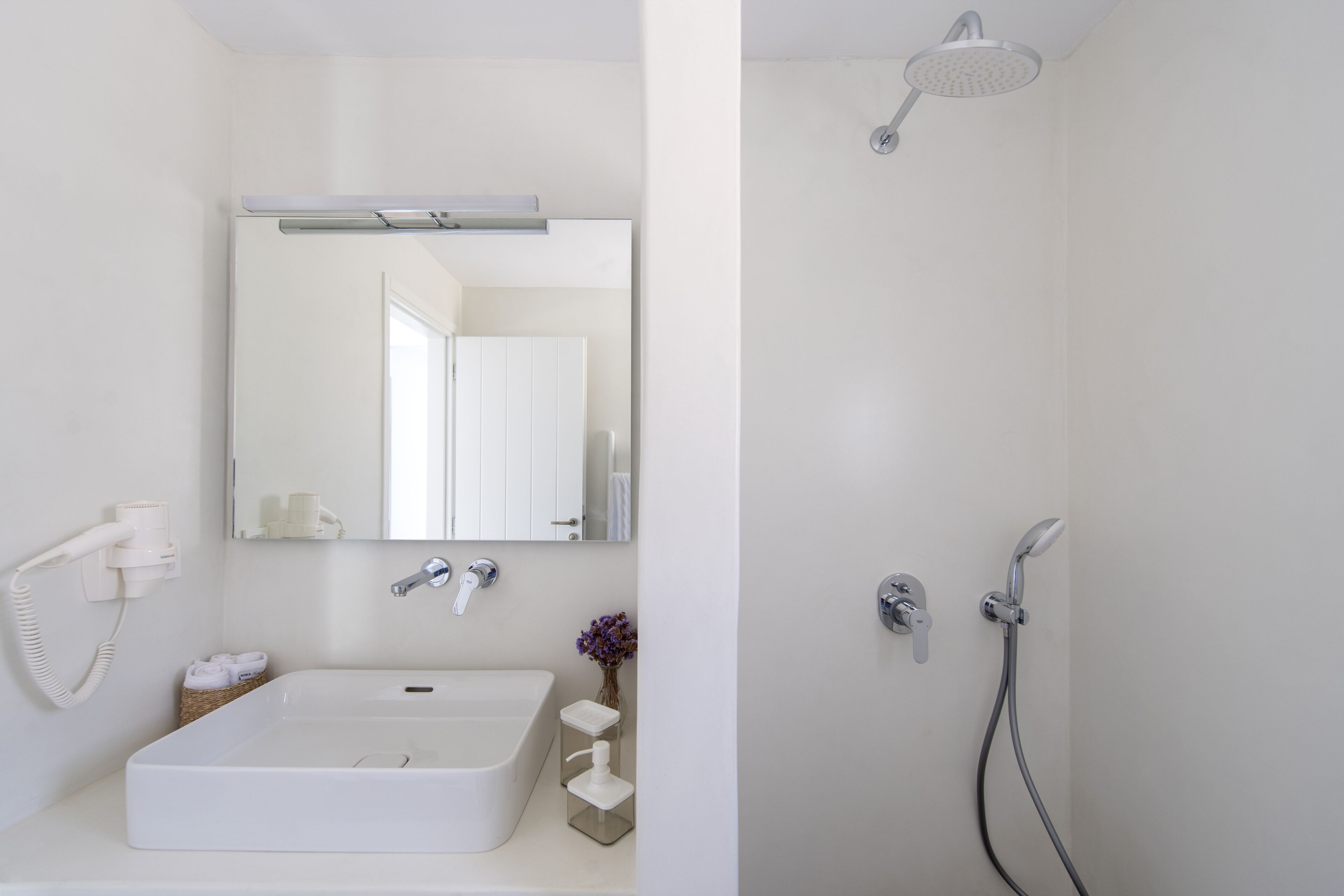 Une salle de bain moderne avec un lavabo blanc, un miroir et une douche.