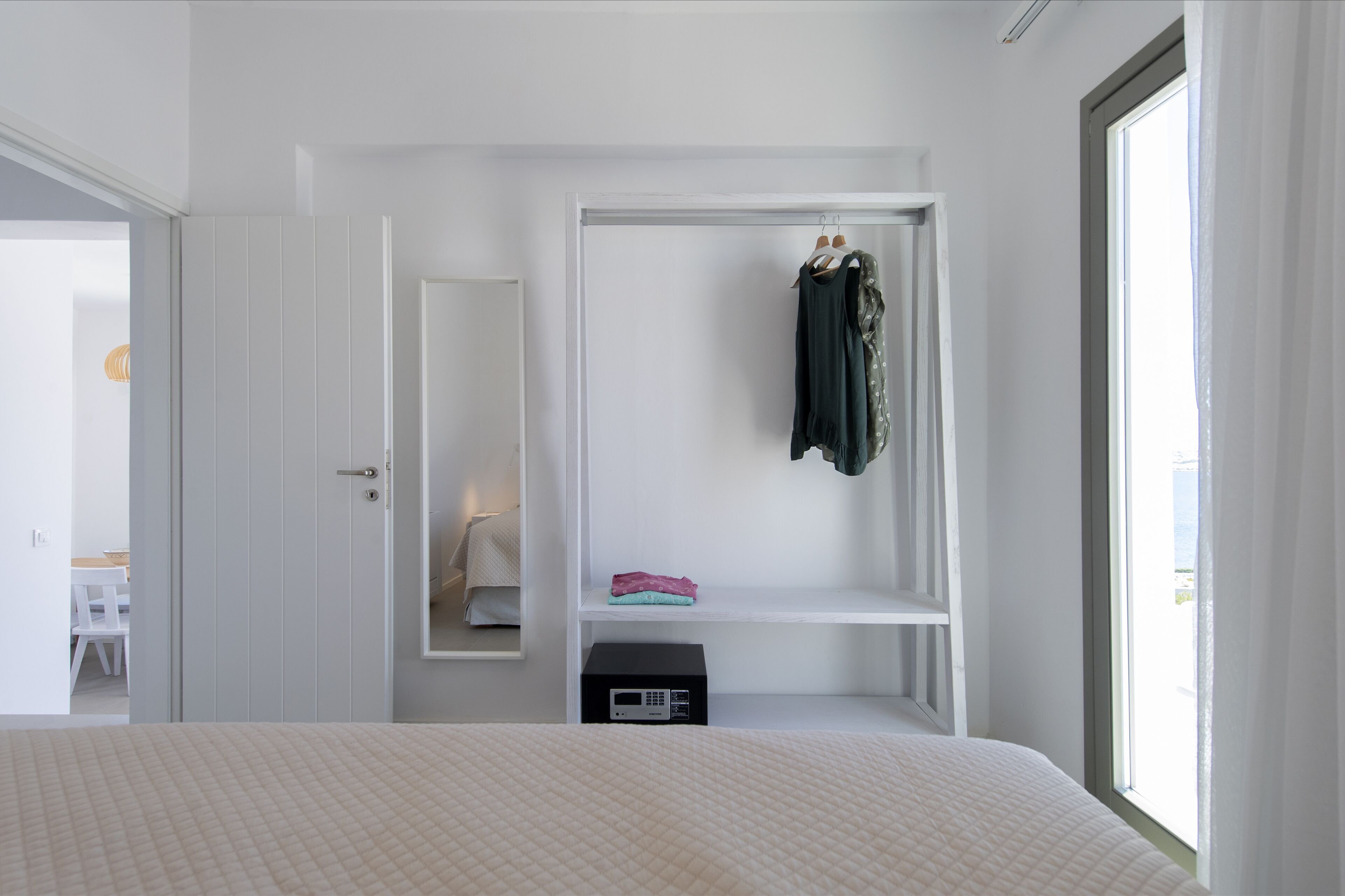 A bedroom with a bed, a wardrobe, and a small table.