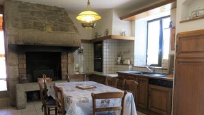 A kitchen with a stone fireplace, wooden cabinets, and a tiled backsplash.