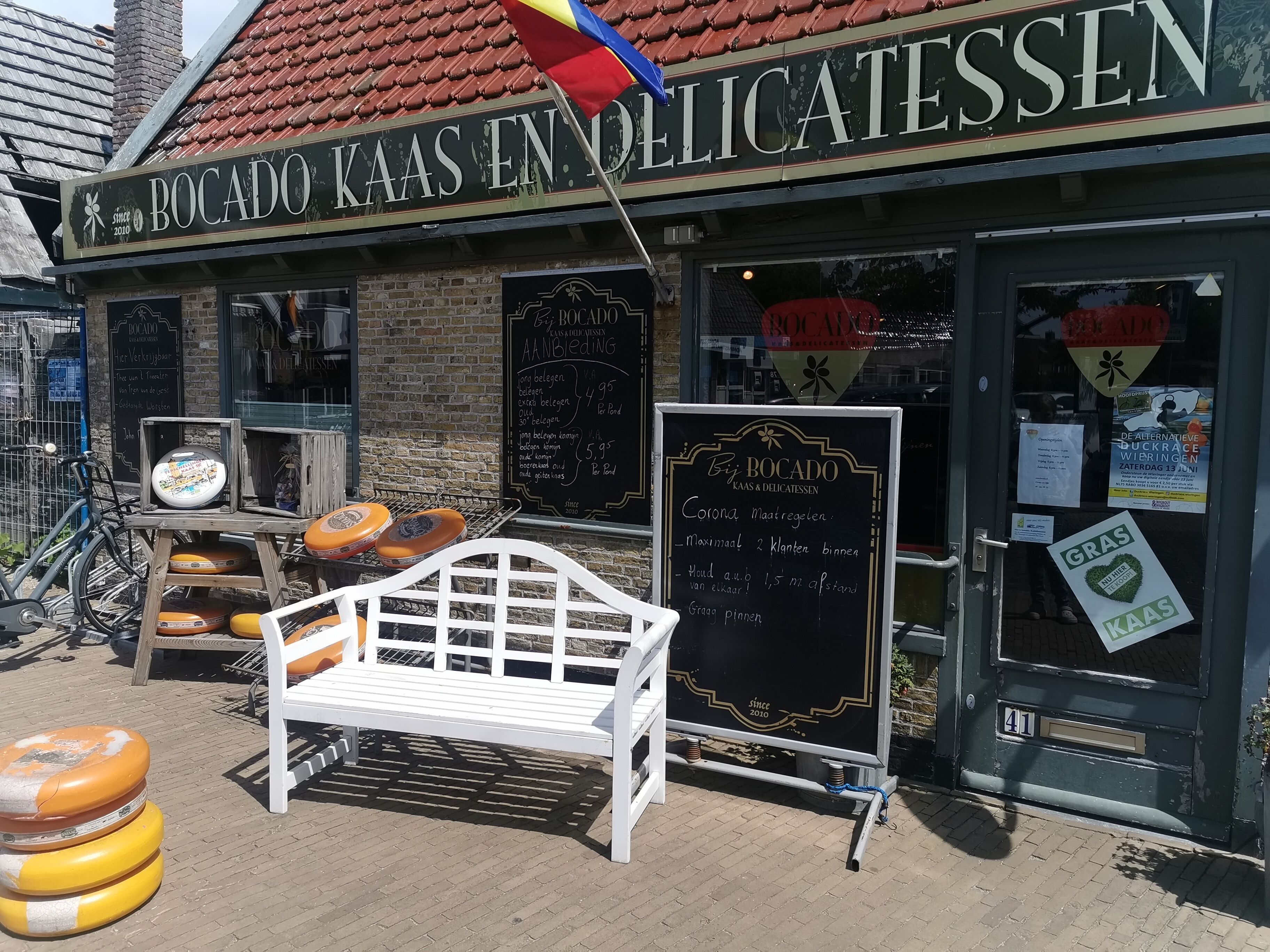 A storefront with a sign reading 'BOCADO KAAS EN DELICATESSEN' and a chalkboard menu outside.