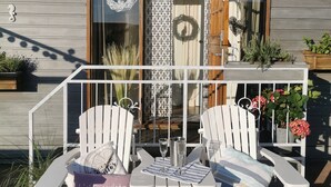 A patio with two white Adirondack chairs, a small table, and a glass of water. - Watten-Blick-Huisje -view of the Wadden Sea (UNESCO World Heritage Site) (Westerland)