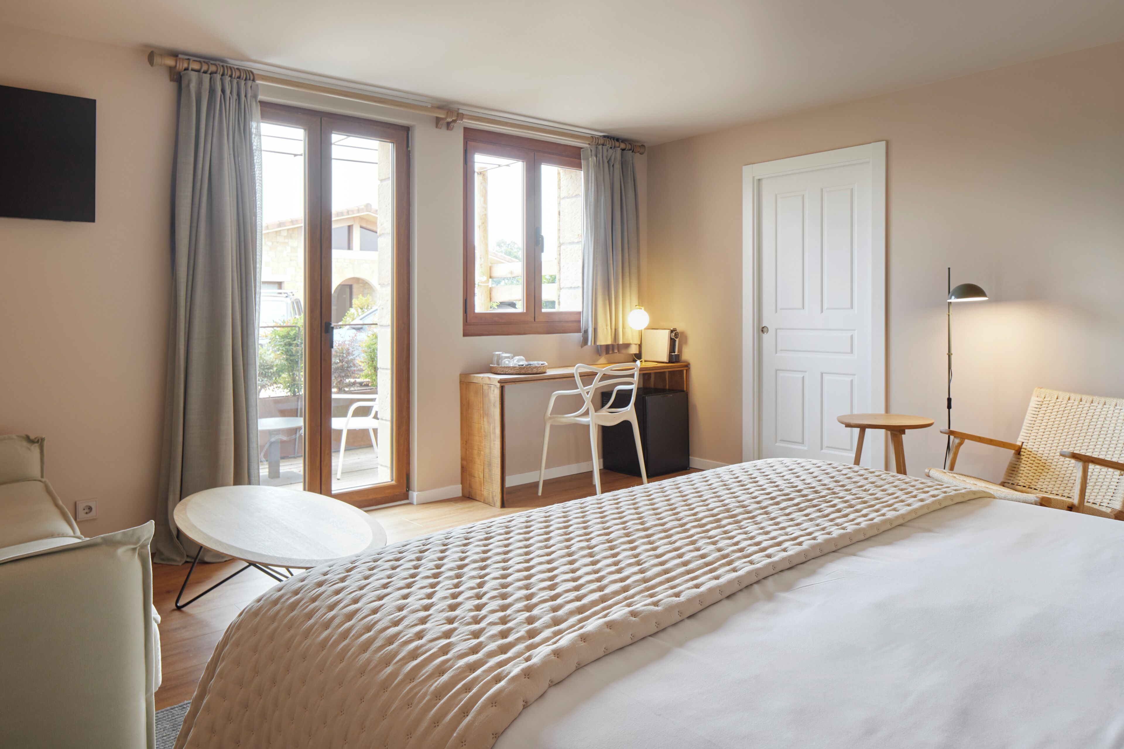 Une chambre d’hôtel avec un lit, un bureau, une chaise, une petite table et une lampe.