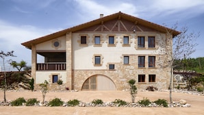 A two-story house with a stone facade, multiple windows, and a large arched entrance. - Olivi1948 - Boutique Guesthouse (Usurbil)