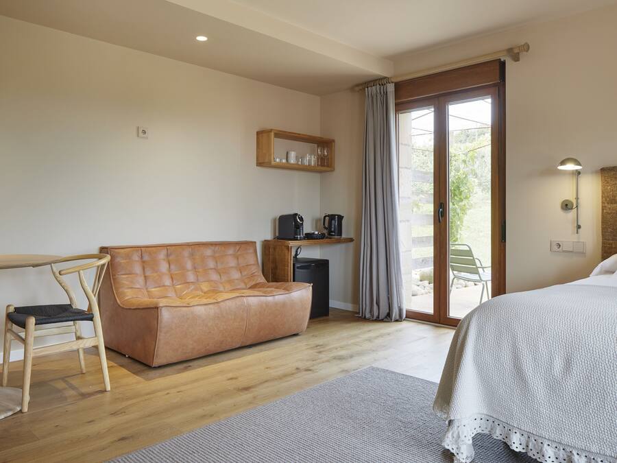 A room with a bed, a sofa, a desk, and a coffee machine.
