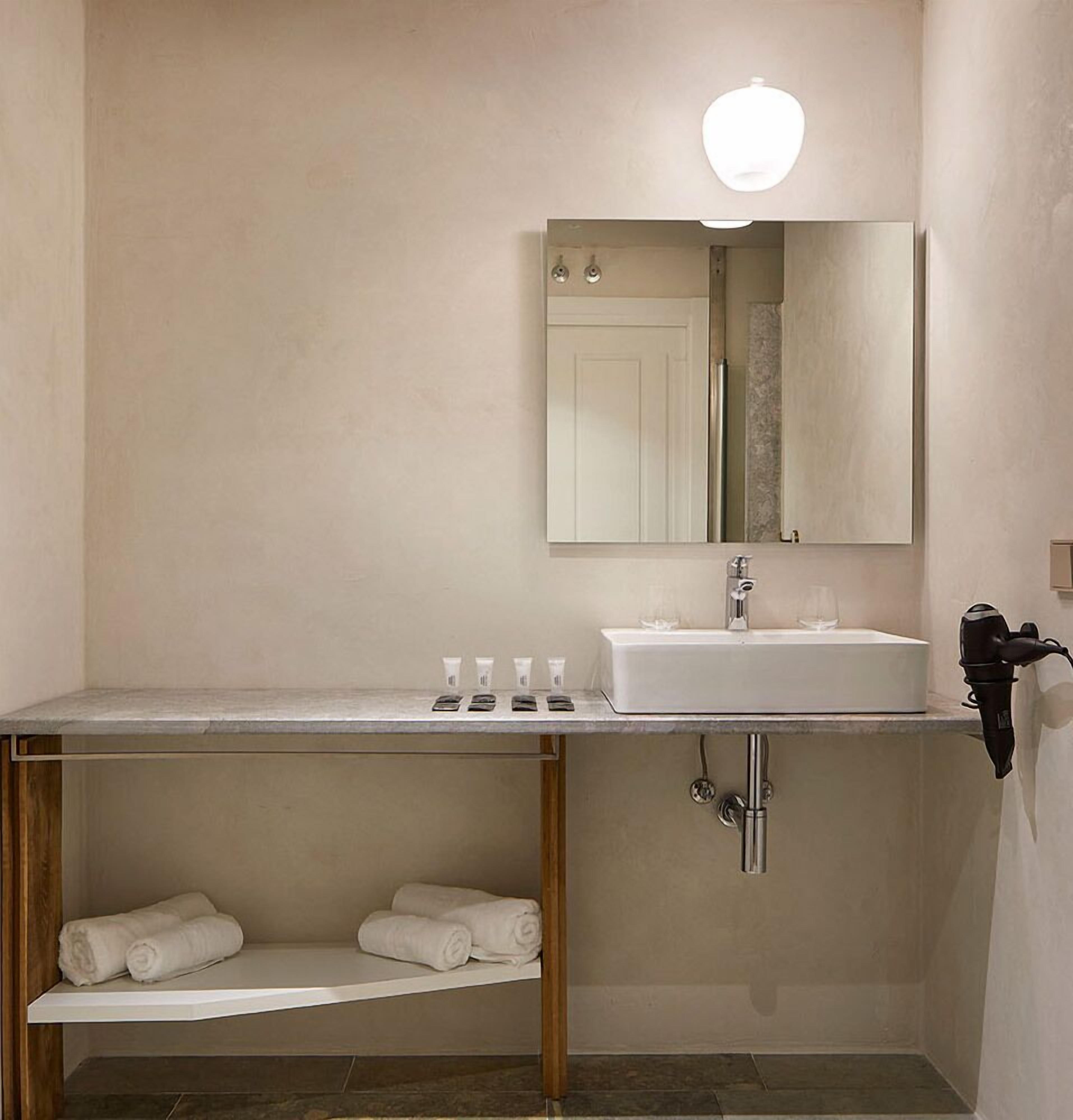 Un baño con lavamanos blanco, espejo y perchero.