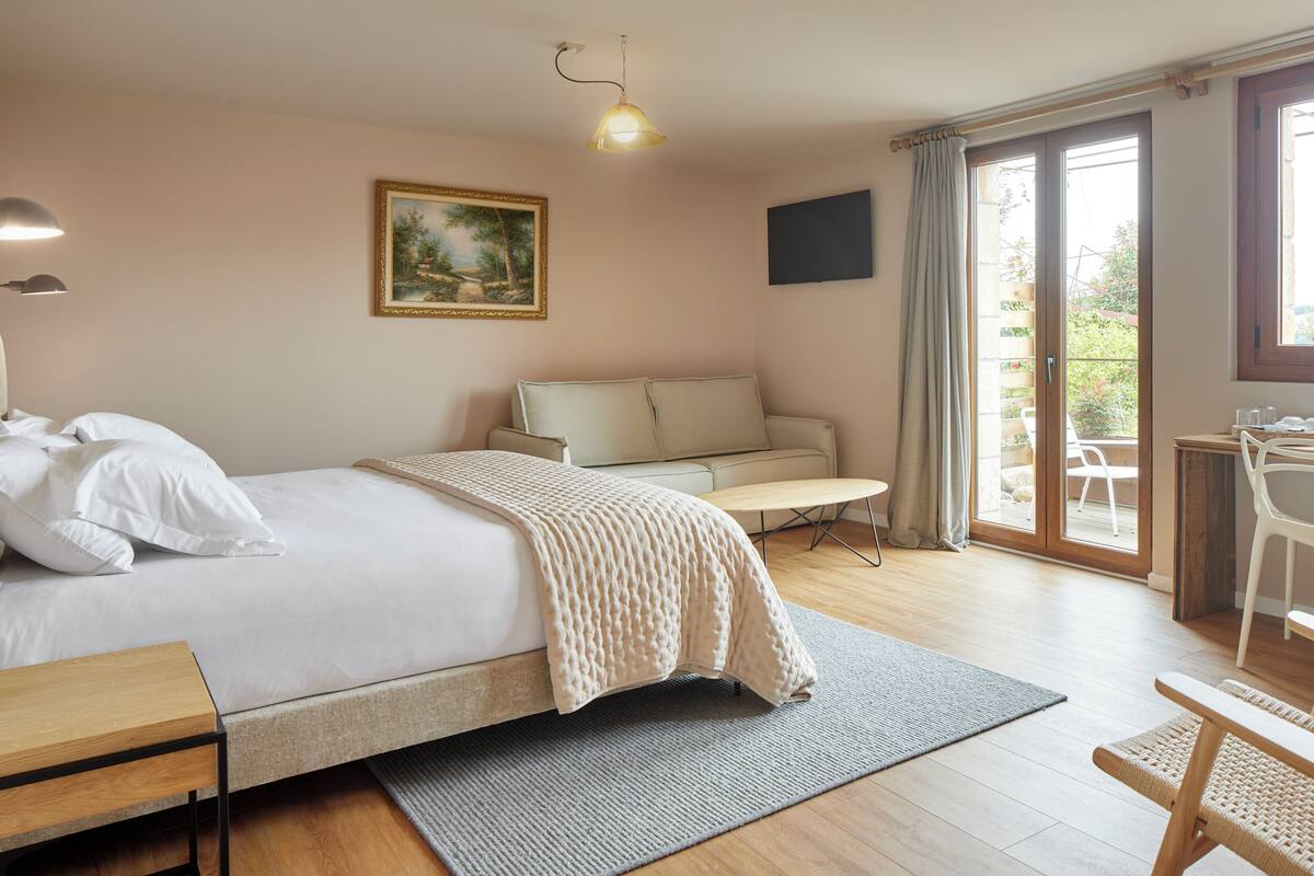 Ein Hotelzimmer mit Bett, Sofa, Schreibtisch und Blick ins Freie.