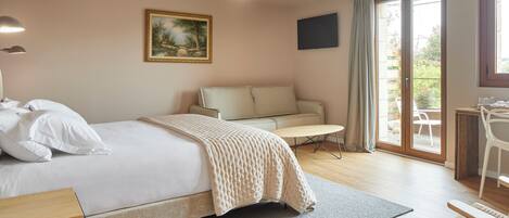 Habitación de hotel con cama, sofá, escritorio y vistas al exterior.