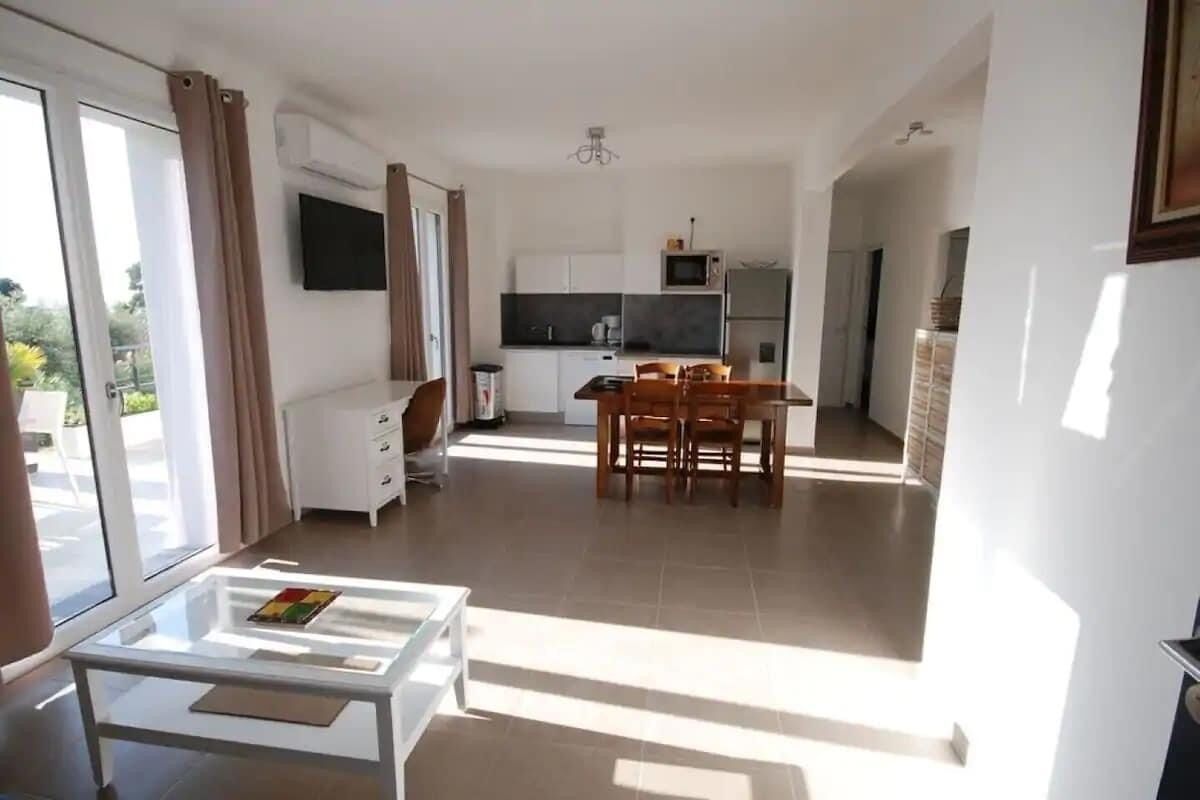 Un apartamento moderno con comedor, cocina y una mesa de vidrio.