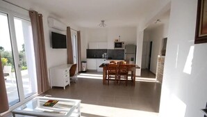 Ein modernes Apartment mit Essbereich, Küche und einem Glastisch.