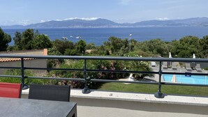 Ein Balkon mit Blick auf das Meer, Boote und Berge.