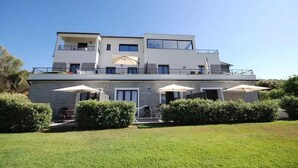 Ein modernes Haus mit zwei Etagen, einem Balkon, einer überdachten Terrasse und einem gepflegten Rasen.