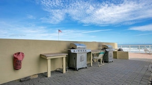 A rooftop patio with barbecue grills, a fire extinguisher, and a flag. - #902 Shores Club Oceanfront Traffic Free Beach 2/2 (Daytona Beach  Shore)