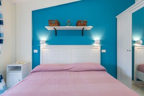 Un dormitorio con cama, mesita de noche, estante con cestas y armario.
