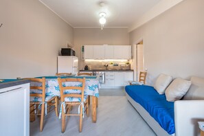 Un espacio habitable compacto con comedor, kitchenette y sofá cama.