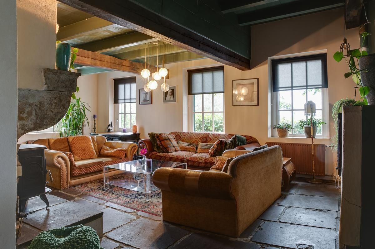 A cozy living room with a fireplace, a sofa, a coffee table, and large windows.