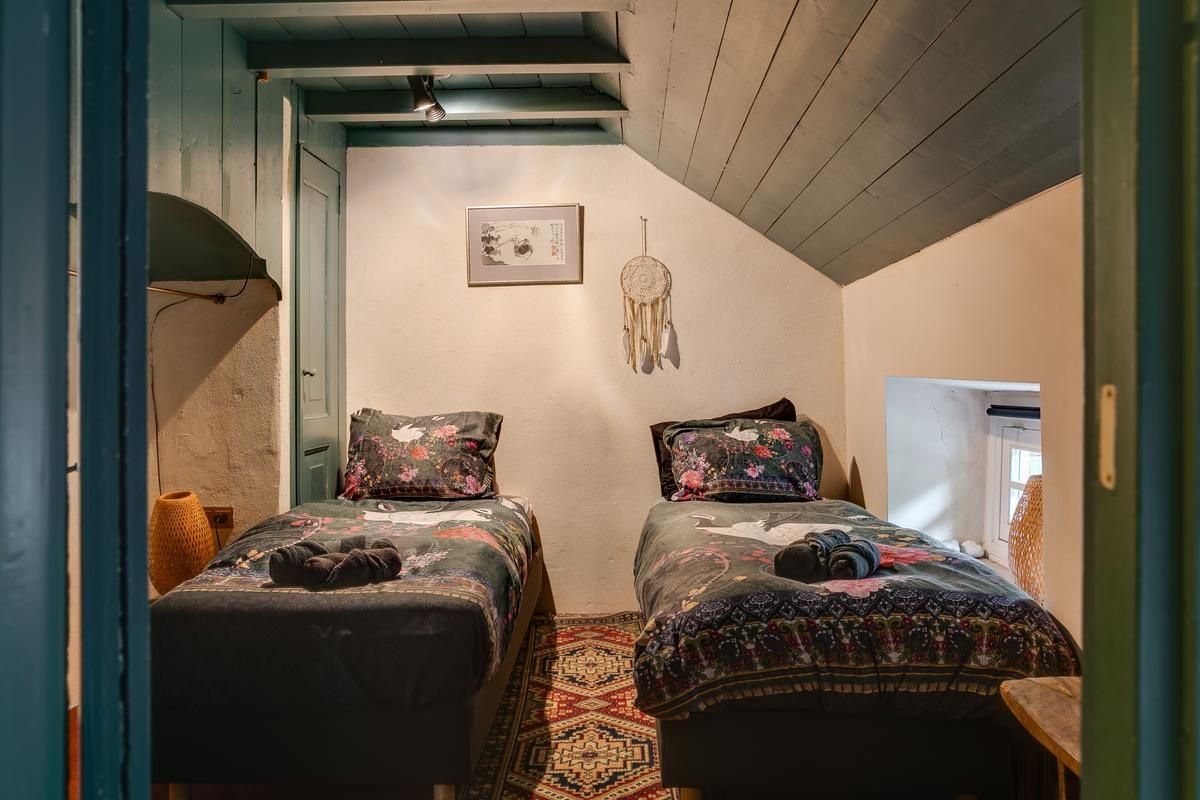 Ein Zimmer mit zwei Betten, einem gemusterten Teppich, einer Wanddekoration und einer Tür.