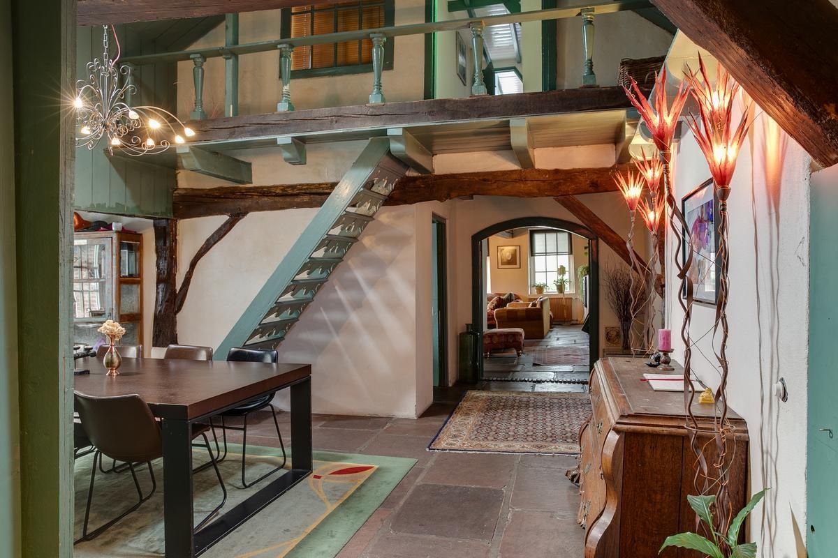 A dining area with a wooden table and chairs, a staircase, and a chandelier.