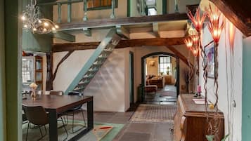 A dining area with a wooden table and chairs, a staircase, and a chandelier.