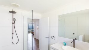 A modern bathroom with a glass shower enclosure, a large mirror, and a view of a balcony with a railing. - Aqua Palm with Sweeping Views of On Mile (Forster)