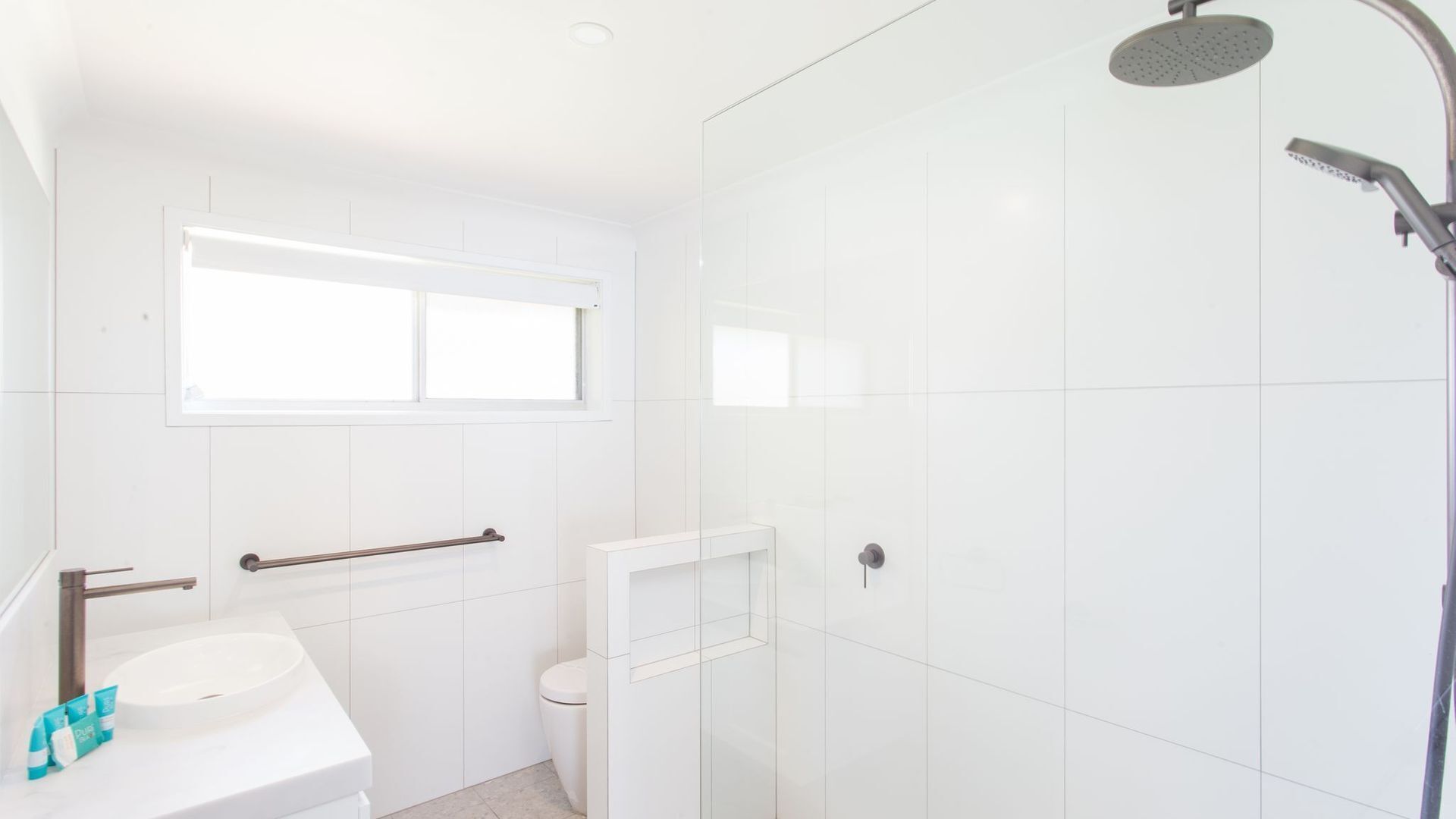 A modern bathroom with a shower, toilet, and sink.