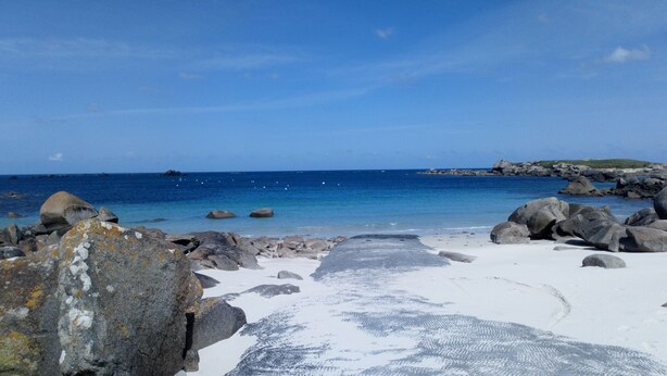 Una playa con rocas grandes y un mar azul y transparente.