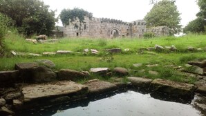 Una estructura de piedra histórica con un pequeño estanque al frente.