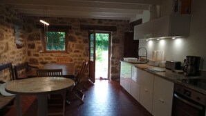 Una cocina rústica con pared de piedra, mesa de madera y suelo de baldosas hexagonales.