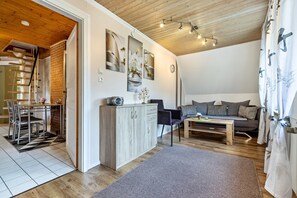 Moderni olohuone, jossa on sohva, sohvapöytä sekä ruokailutila tuoleineen ja pöytineen.