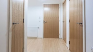 A hallway with wooden doors, a white radiator, and a ceiling light fixture. - Stylish 2 Bedroom Apartment Aberdeen City Centre (Aberdeen)