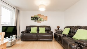 A living room with two brown leather sofas, a flat-screen TV, a wooden coffee table, and a painting on the wall. - Stylish 2 Bedroom Apartment Aberdeen City Centre (Aberdeen)