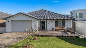 A single-story house with a garage, a front porch with a bench, and a small garden area. - Amaroo - Uninterrupted 180 degree water views (Gerroa)