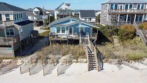 A beachfront property with multiple houses, including a prominent blue house with a deck and stairs leading to a beach. - Discover Sea La Vie: an oceanfront 3-bedroom haven in Surf City, perfect for families! (Surf City)