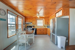 A kitchen with wooden cabinets, a refrigerator, a stove, and a dining table with chairs.