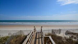 A wooden boardwalk leading to a beach with clear skies. - Discover Sea La Vie: an oceanfront 3-bedroom haven in Surf City, perfect for families! (Surf City)
