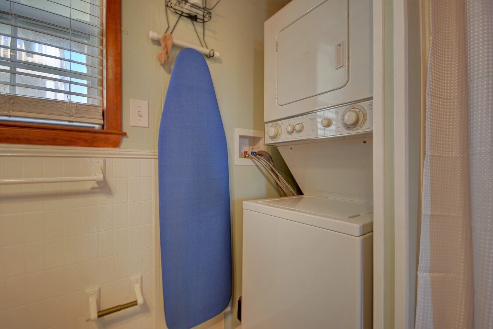 A laundry room with a washing machine, dryer, and ironing board.