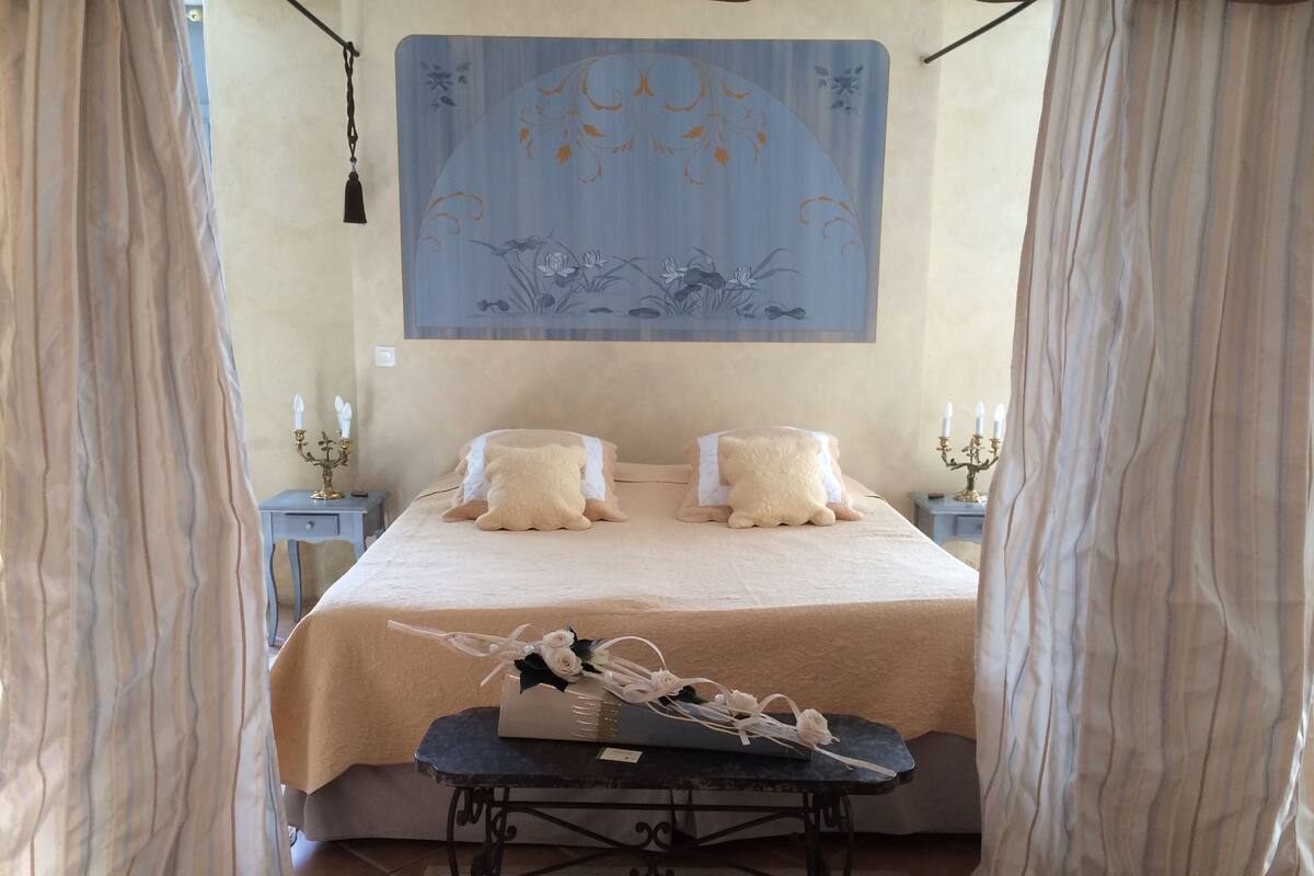 A neatly arranged bedroom with a bed, two bedside tables, and a decorative wall hanging.
