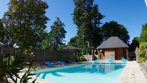 A swimming pool with blue lounge chairs, a wooden deck, and a small building with a sloped roof. - Clos des 3 Rois Chambres Hôtes Thouarcé (Bellevigne-en-Layon)