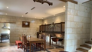 A spacious kitchen with a dining area, wooden furniture, and a staircase. - Clos des 3 Rois Chambres Hôtes Thouarcé (Bellevigne-en-Layon)