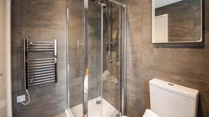 Un baño moderno con ducha envuelta en vidrio, un perchero y un inodoro.