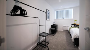 Habitación pequeña con literas, una mesita de noche, un radiador y una ventana con persianas.
