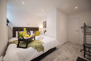 Un dormitorio ordenado con cama, mesita de noche y perchero.