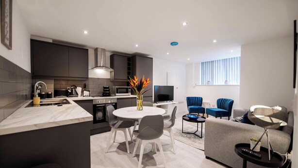 Una cocina moderna con comedor, televisor de pantalla plana y sala de estar con sillas azules.