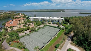 A hotel with multiple tennis courts, a swimming pool, and a view of a large body of water. - Beautiful bayfront view! December 2026 dates available now! (Longboat Key)